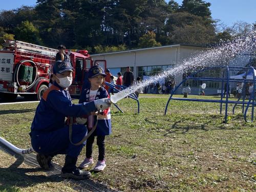 消防の衣装を着て放水している幼児の様子