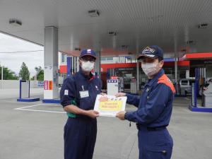 消防職員が給油取扱所の職員に誤給油の注意喚起するチラシを手渡ししている様子