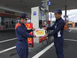 消防職員が給油取扱所の職員に誤給油の注意喚起するチラシを手渡ししている様子
